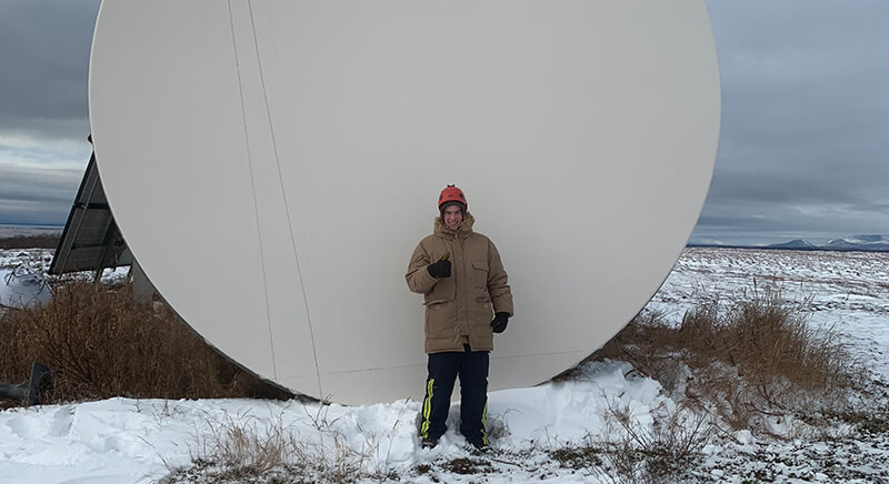 Alaris mWave team member in front of antenna dish
